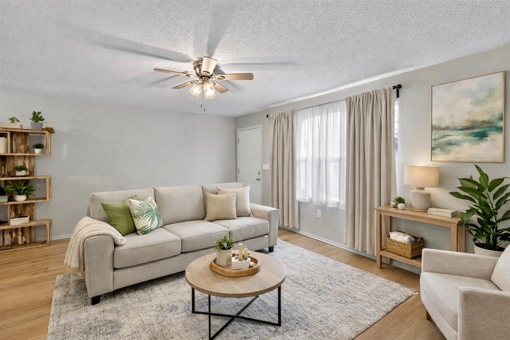 A living room features a light gray sofa, round coffee table, and wood-toned flooring — 11920 DIETZ DRIVE UNIT 11920, TAMPA, FL
