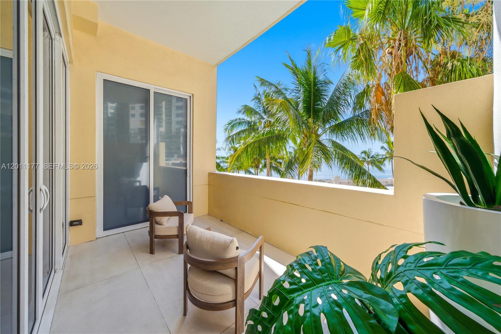 A balcony features two wooden chairs, light tile flooring, and views of palm trees — 808 Brickell Key Dr # 408, Miami FL 33131, MIAMI, FL