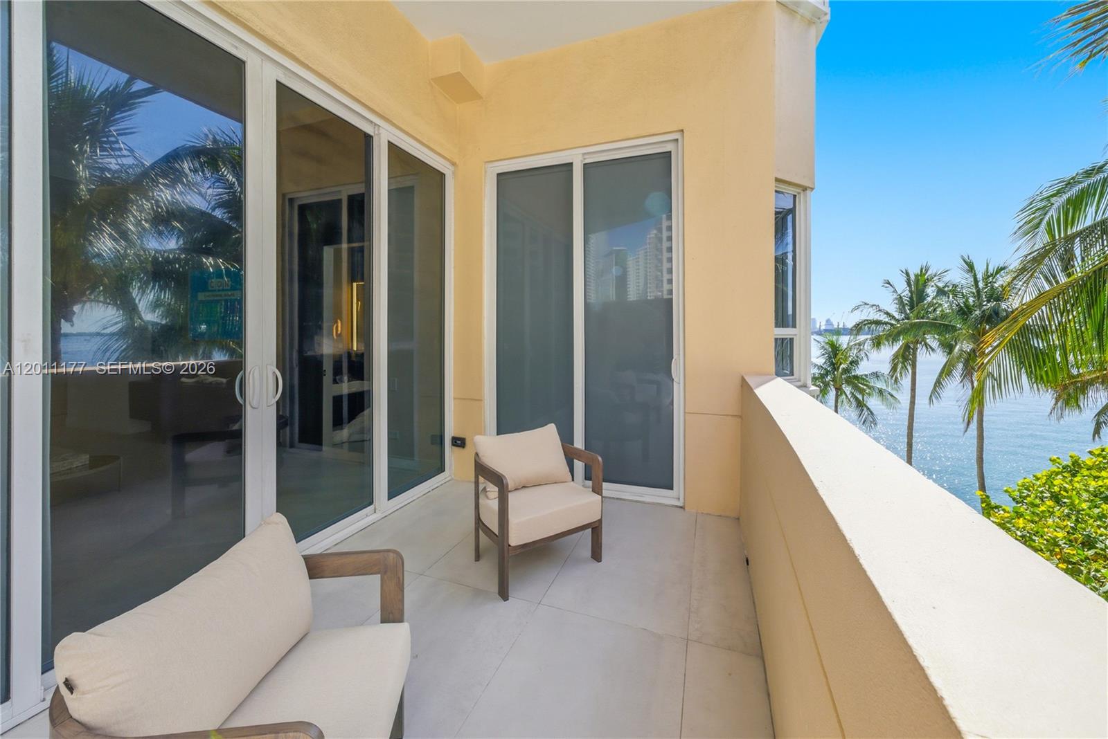 A balcony with two chairs overlooks the ocean and palm trees — 808 Brickell Key Dr # 408, Miami FL 33131, MIAMI, FL