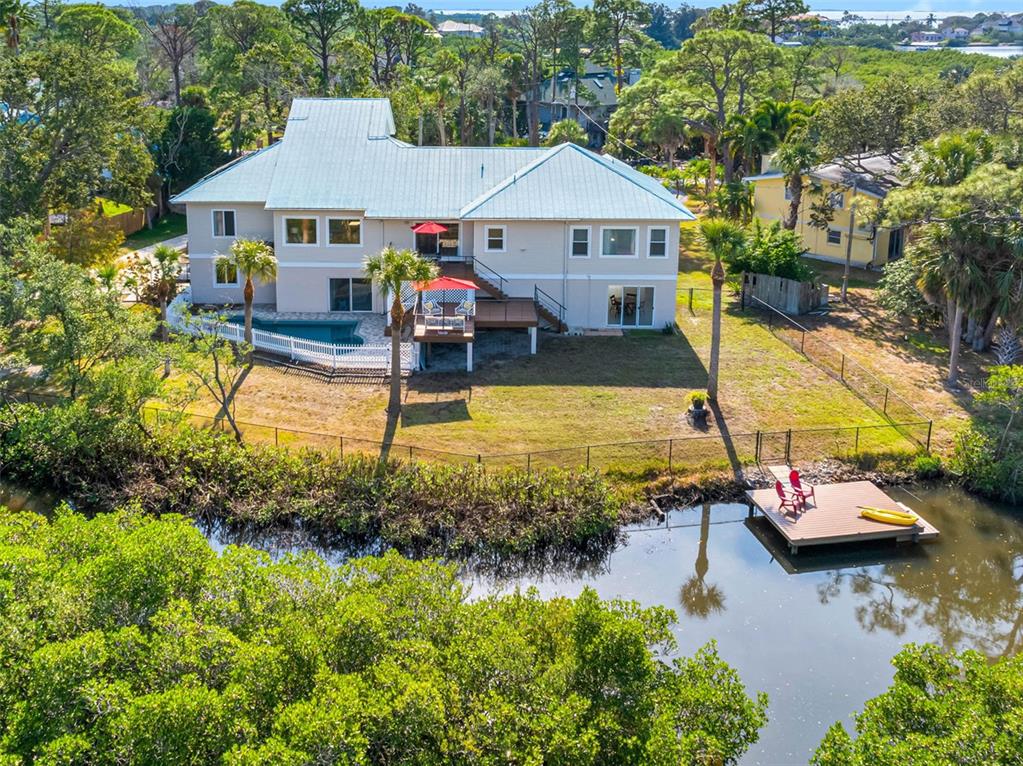 An aerial view of a two-story house with a metal roof, pool, and private dock — 1580 MACCHESNEY DRIVE, TARPON SPRINGS, FL