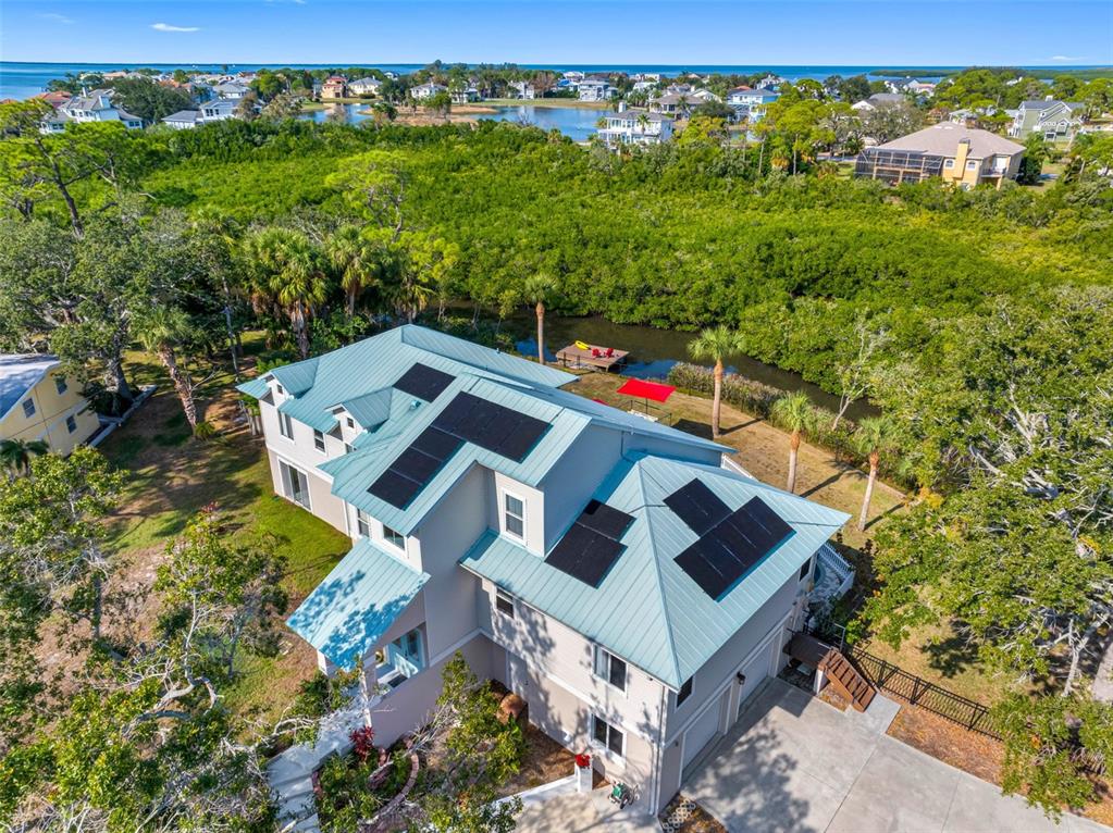 An aerial view of a multi-story house with a metal roof and solar panels — 1580 MACCHESNEY DRIVE, TARPON SPRINGS, FL