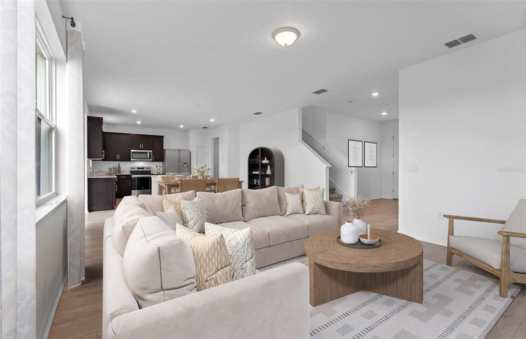 A living room with a beige sectional sofa, round coffee table, and open-concept kitchen — 1277 LAKERIDGE WAY, LAKE ALFRED, FL