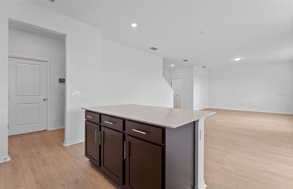 A kitchen island with dark cabinets and a light countertop sits in an open-concept room — 1277 LAKERIDGE WAY, LAKE ALFRED, FL