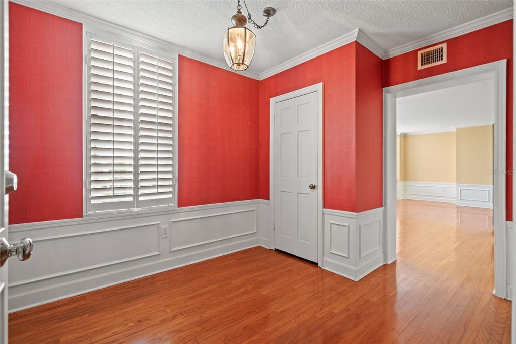 A room with red walls, white wainscoting, hardwood floors, a shuttered window, and a chandelier — 2407 S ARDSON PLACE UNIT 501A, TAMPA, FL