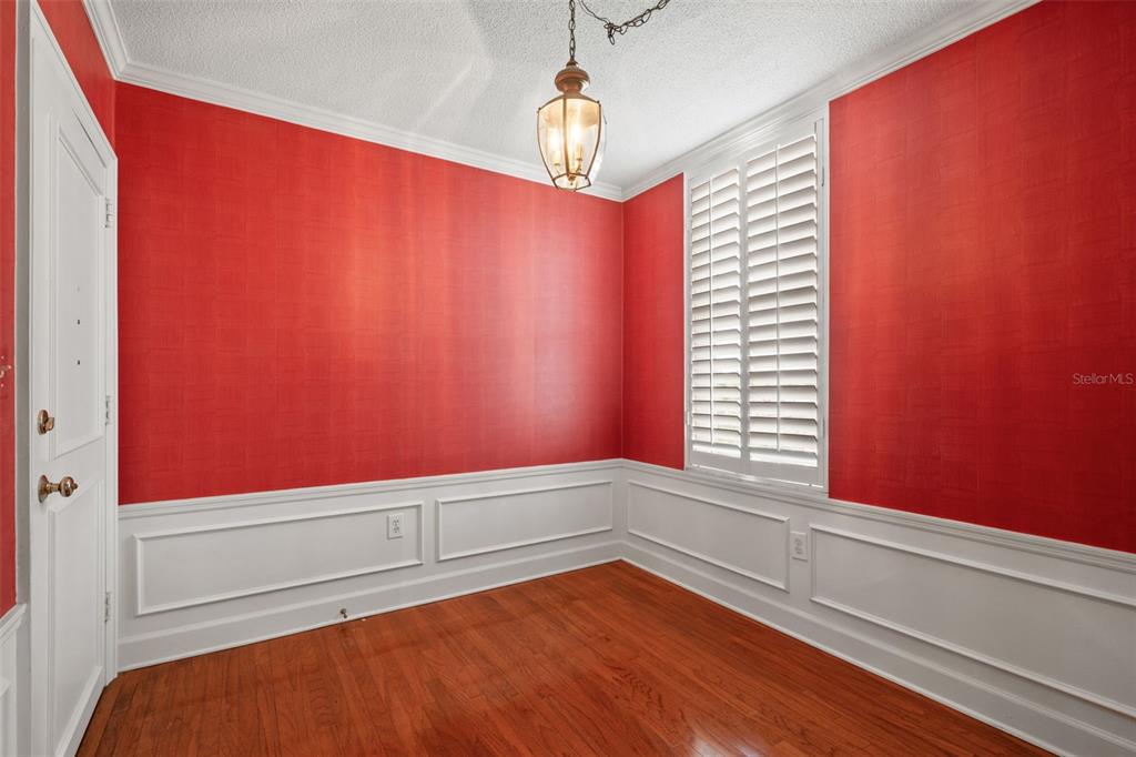 An empty room features red wallpaper, white wainscoting, hardwood floors, and a hanging light fixture — 2407 S ARDSON PLACE UNIT 501A, TAMPA, FL