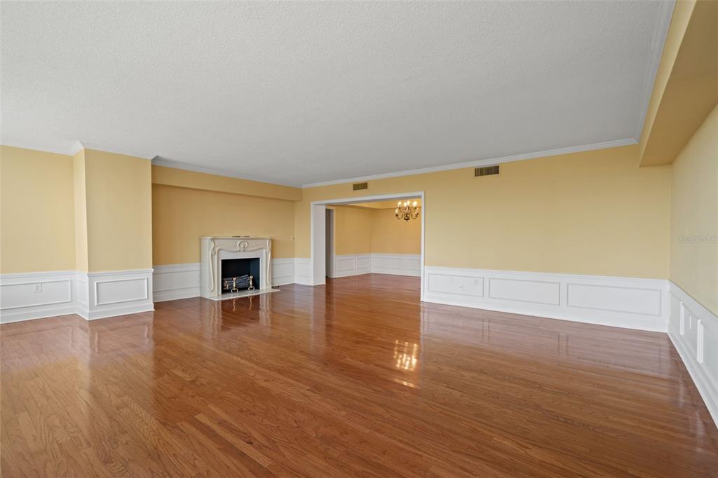 An empty living room features hardwood floors, white wainscoting, yellow walls, and a fireplace — 2407 S ARDSON PLACE UNIT 501A, TAMPA, FL