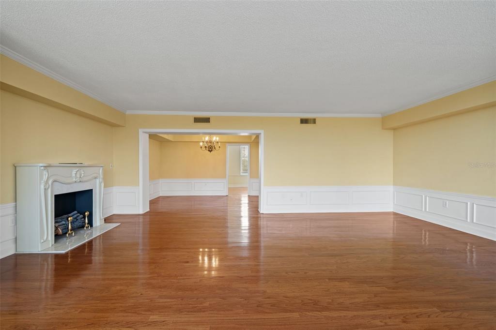 An empty living room features hardwood floors, yellow walls with wainscoting, and a white fireplace — 2407 S ARDSON PLACE UNIT 501A, TAMPA, FL