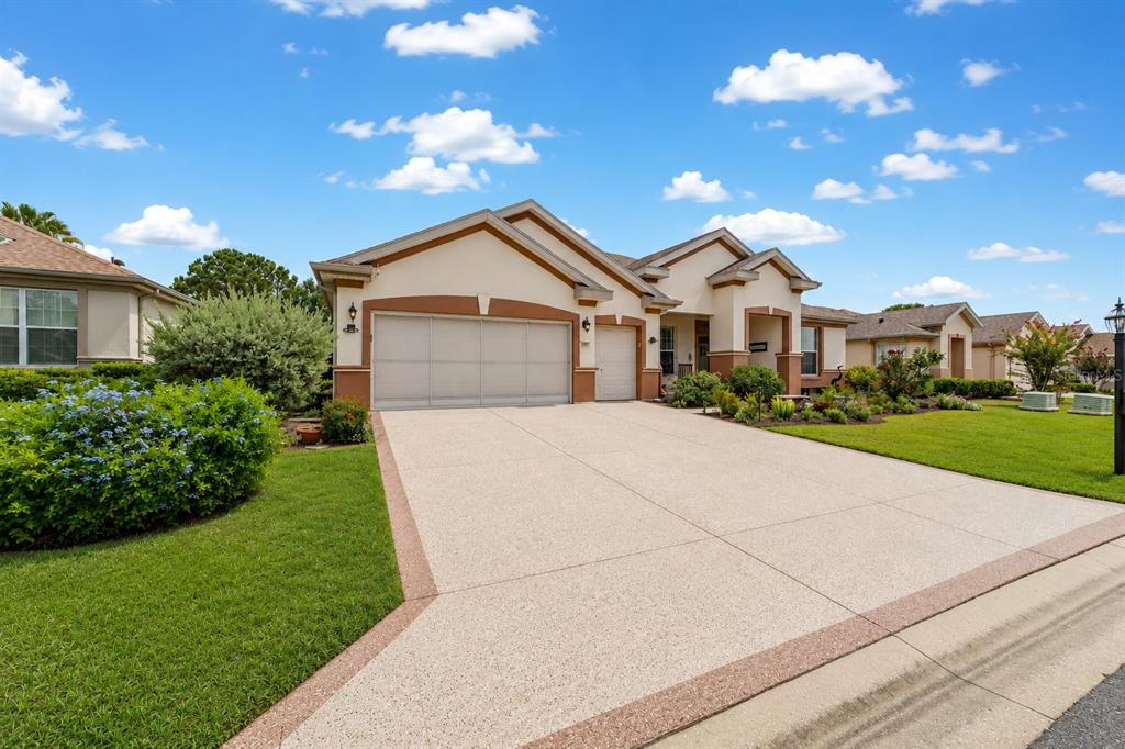 A single-story suburban house with a beige stucco exterior, brown trim, and a concrete driveway — 9361 SE 137TH STREET ROAD, SUMMERFIELD, FL