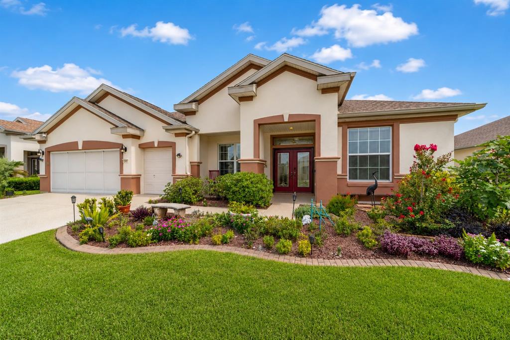 A single-story house with a beige stucco exterior, brown trim, and a landscaped front yard — 9361 SE 137TH STREET ROAD, SUMMERFIELD, FL