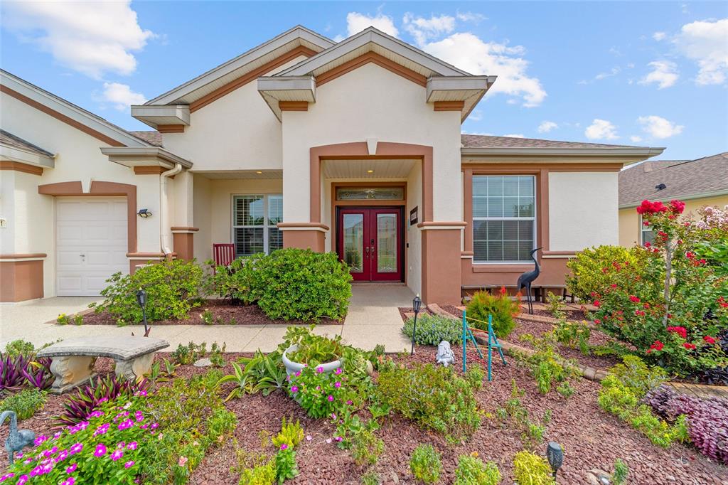 A single-story house exterior features a red double front door and a landscaped front yard — 9361 SE 137TH STREET ROAD, SUMMERFIELD, FL