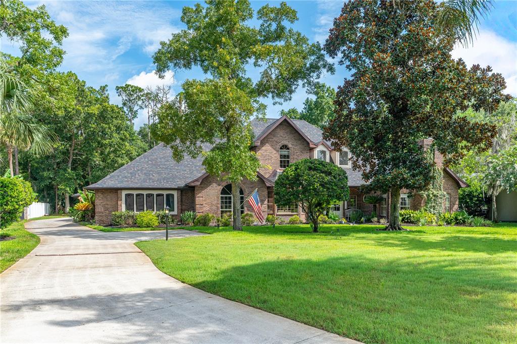 A two-story brick house with a large front lawn and a concrete driveway — 73 SHADOW CREEK WAY, ORMOND BEACH, FL