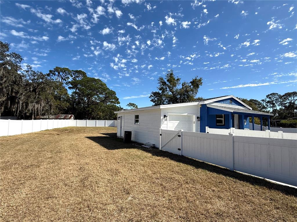 A white house with a blue accent wall and a white vinyl fence in the yard — 2701 BROOKLINE AVENUE, NEW SMYRNA BEACH, FL