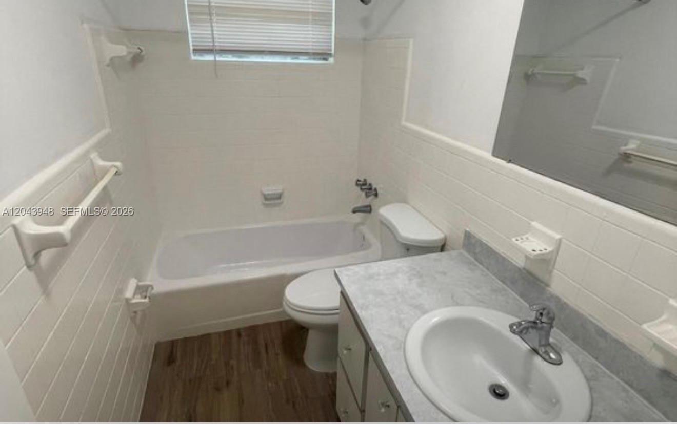 A bathroom features a white tub-shower combo, a vanity with a sink, and tiled walls — 400 SE 9th Ct # 9, Hallandale Beach FL 33009, HALLANDALE BEACH, FL