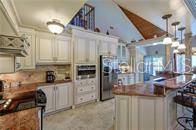 A kitchen features white cabinetry, granite countertops, stainless steel appliances, and a vaulted ceiling — 1740 NW 20TH AVENUE, CRYSTAL RIVER, FL