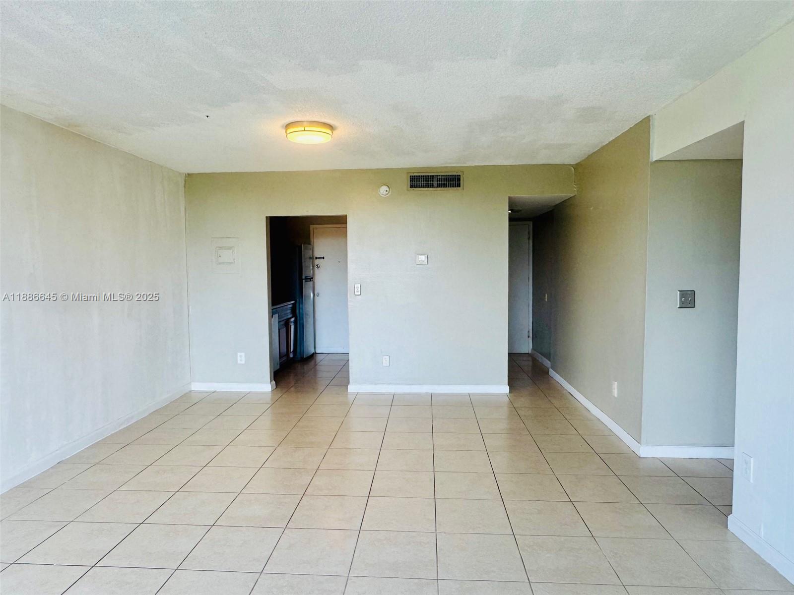 An empty room with beige tile flooring, light-colored walls, and two doorways — 2000 NE 135th St # 403, North Miami FL 33181, NORTH MIAMI, FL
