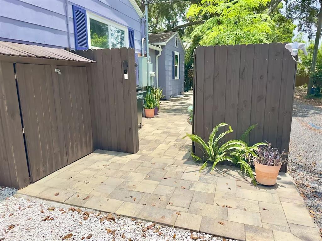 A paved walkway leads between two wooden fences toward a light blue house exterior — 5214 27TH AVENUE S UNIT 2, GULFPORT, FL