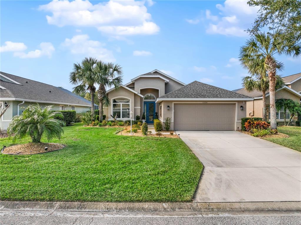 A single-story suburban house with a tan stucco exterior, a two-car garage, and palm trees — 1234 CROWN POINTE LANE, ORMOND BEACH, FL