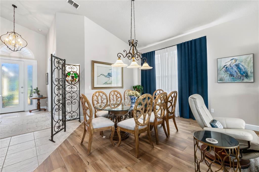 A dining room features a glass-topped table, ornate chairs, a chandelier, and blue curtains — 1234 CROWN POINTE LANE, ORMOND BEACH, FL