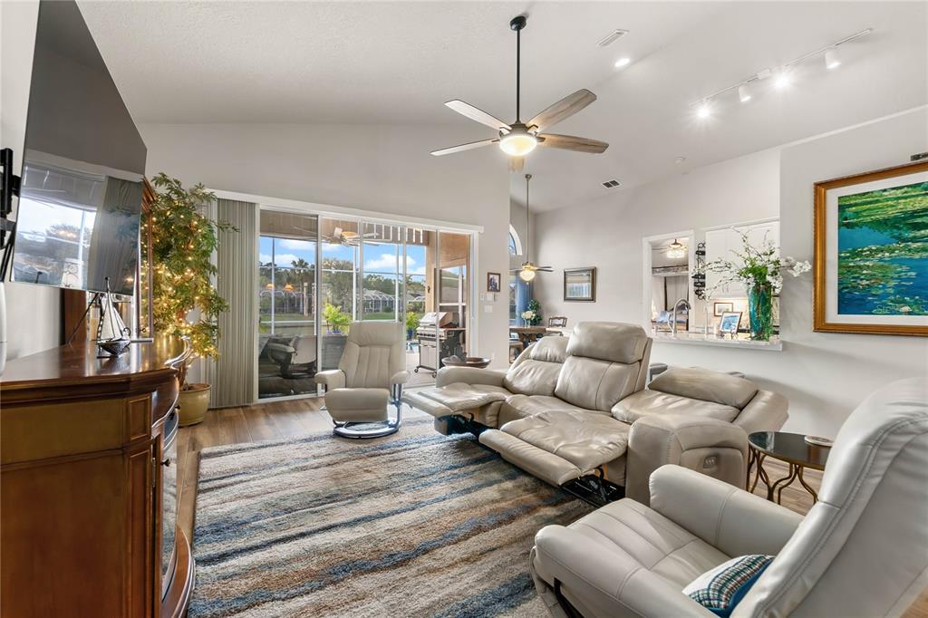 A living room features a reclining sofa, armchairs, a striped rug, and sliding glass doors — 1234 CROWN POINTE LANE, ORMOND BEACH, FL