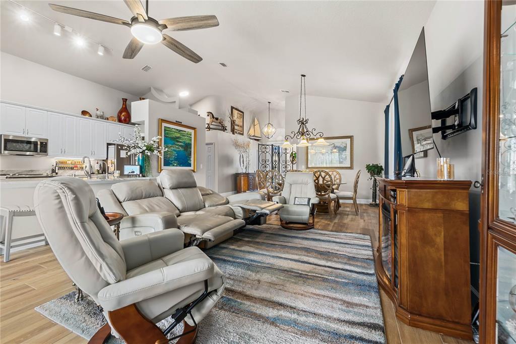 A living room with light-colored leather recliners, a striped area rug, and an open kitchen — 1234 CROWN POINTE LANE, ORMOND BEACH, FL