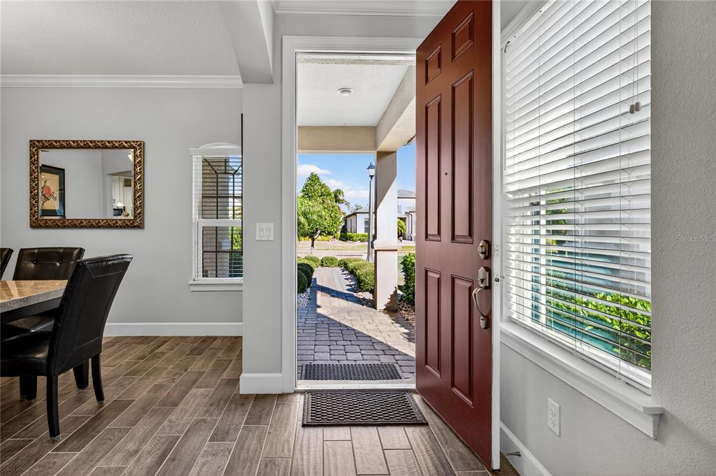 An open front door reveals a paved walkway leading to a sunny residential street — 1284 ZEEK RIDGE STREET, CLERMONT, FL