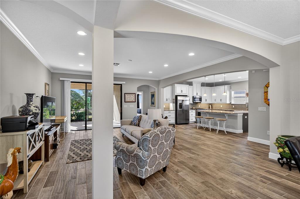 An open-concept living room flows into a kitchen with white cabinets and a breakfast bar — 1284 ZEEK RIDGE STREET, CLERMONT, FL