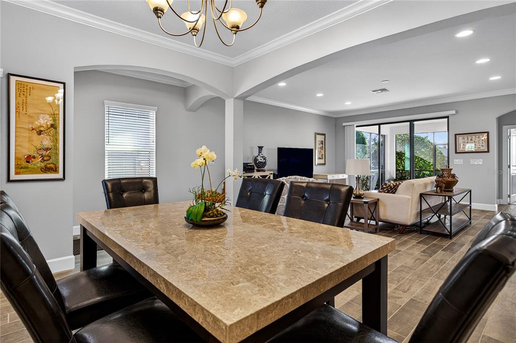 A dining room with a stone-topped table and leather chairs opens into a living area — 1284 ZEEK RIDGE STREET, CLERMONT, FL