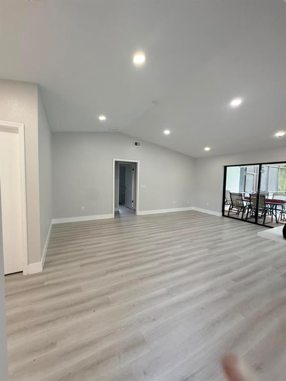 A spacious, light-filled room features light wood-look flooring, recessed lighting, and a sliding glass door — 11189 LINDEN DRIVE, SPRING HILL, FL
