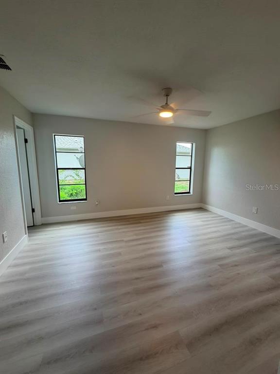An empty bedroom features light-colored wood-look flooring, two windows, and a ceiling fan — 11189 LINDEN DRIVE, SPRING HILL, FL