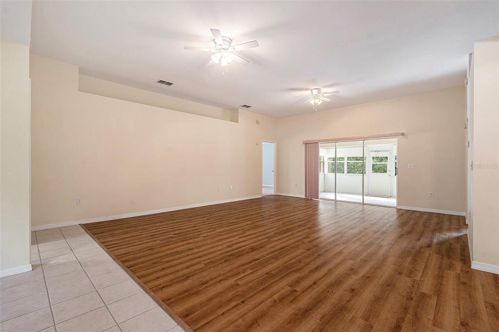 A spacious living room features light-colored walls, wood-look flooring, and two ceiling fans — 29418 SCHINNECOCK HILLS LANE, SAN ANTONIO, FL