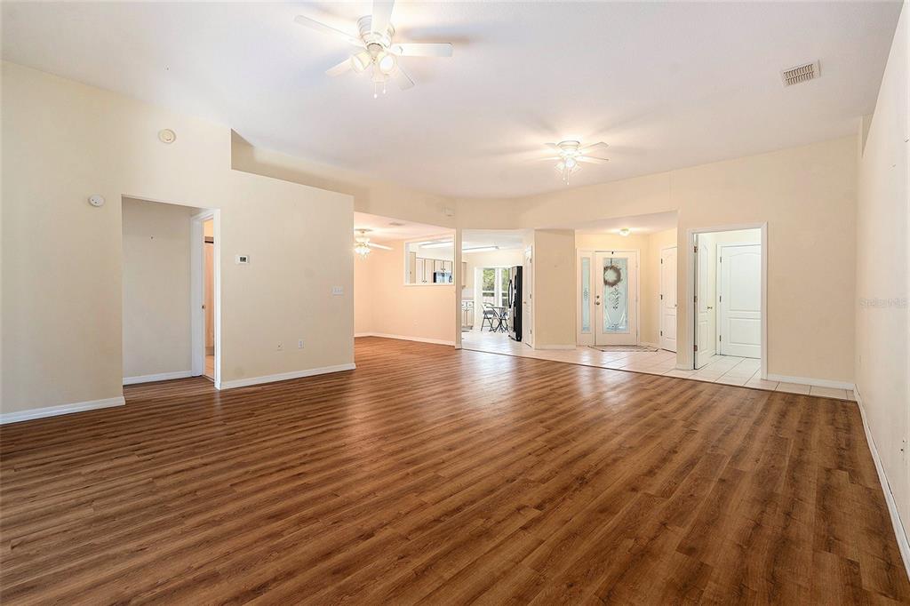 A spacious living area with wood-look flooring, ceiling fans, and an open floor plan — 29418 SCHINNECOCK HILLS LANE, SAN ANTONIO, FL