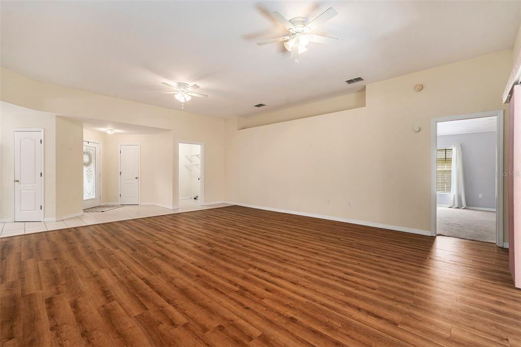 A spacious living room features light-colored walls, two ceiling fans, and wood-look flooring — 29418 SCHINNECOCK HILLS LANE, SAN ANTONIO, FL