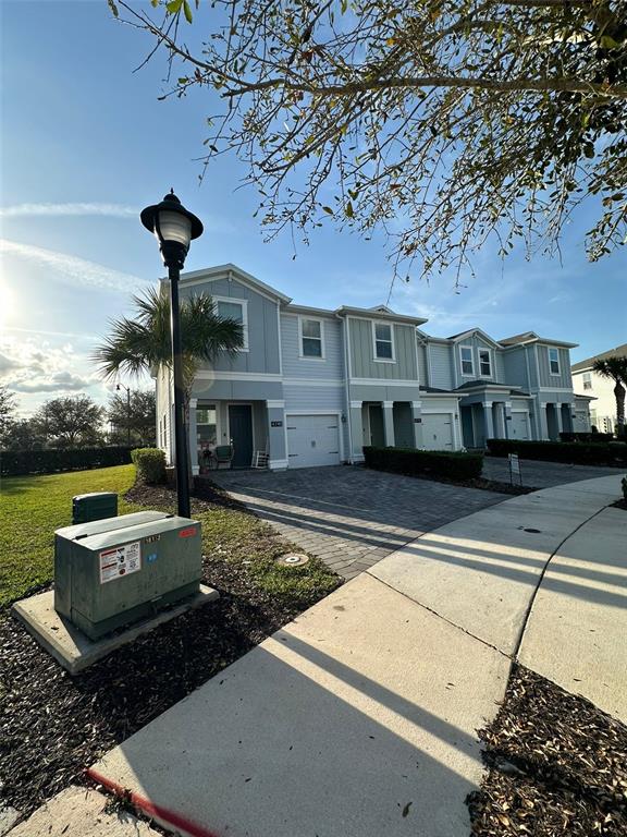 A row of light blue townhouses with paved driveways and a street lamp in the foreground — 4740 TRIBUTE TRAIL, KISSIMMEE, FL
