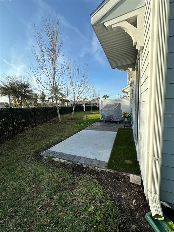 A small concrete patio sits beside a house with a white downspout and siding — 4740 TRIBUTE TRAIL, KISSIMMEE, FL