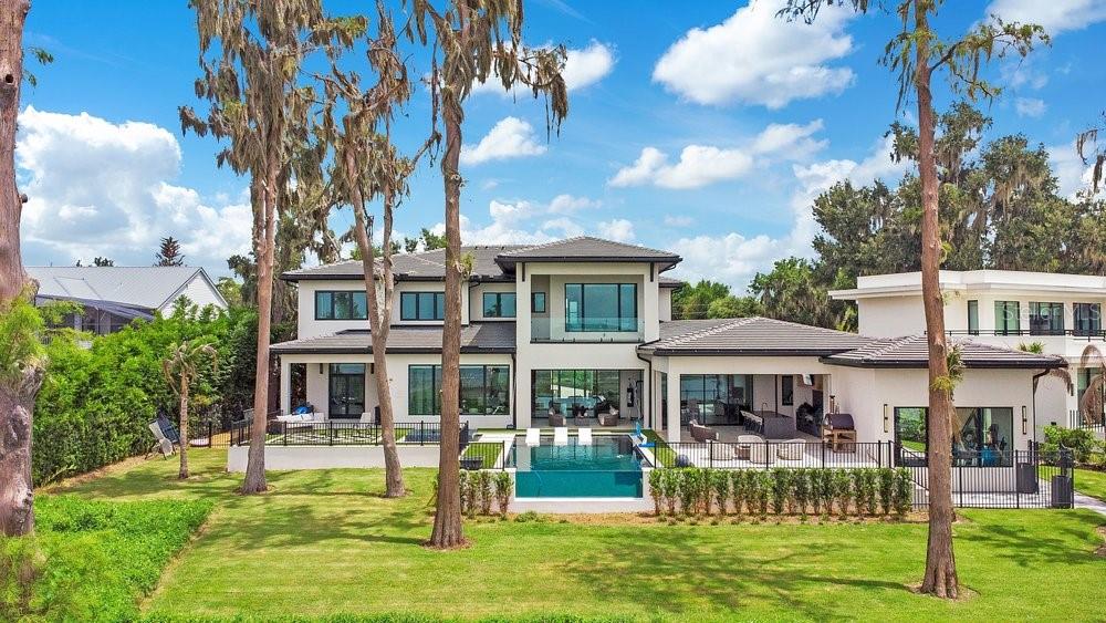 A modern two-story house features a glass-walled infinity pool and a spacious backyard patio — 724 W 2ND AVENUE, WINDERMERE, FL