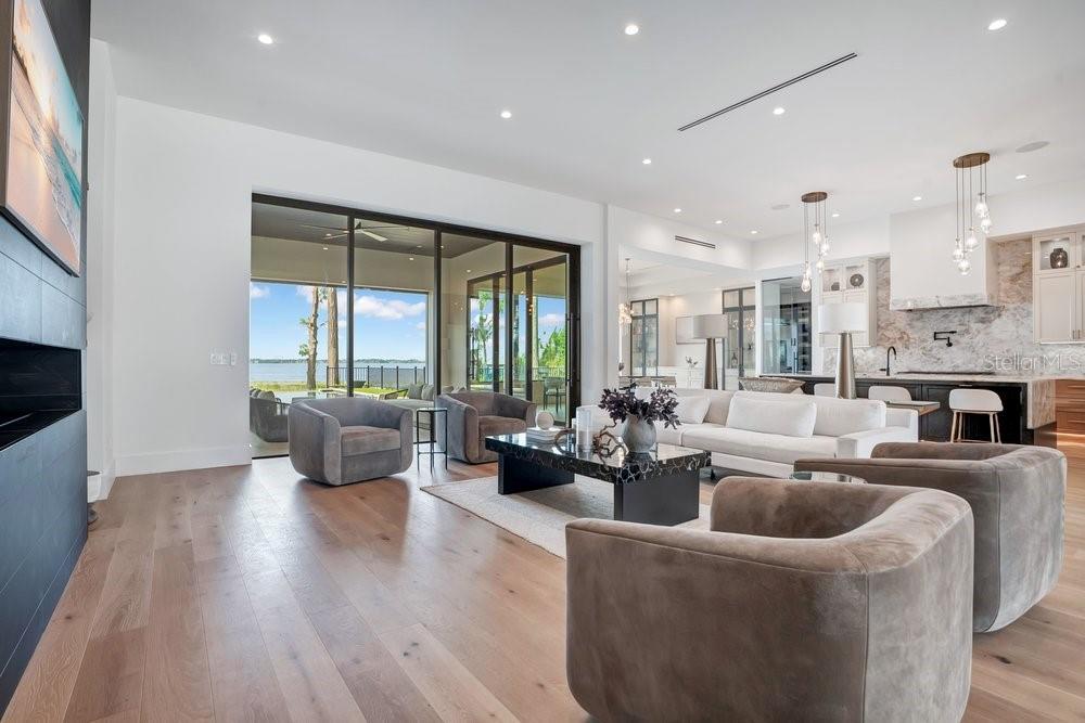 A modern living room with light wood floors, a white sofa, and large sliding glass doors — 724 W 2ND AVENUE, WINDERMERE, FL