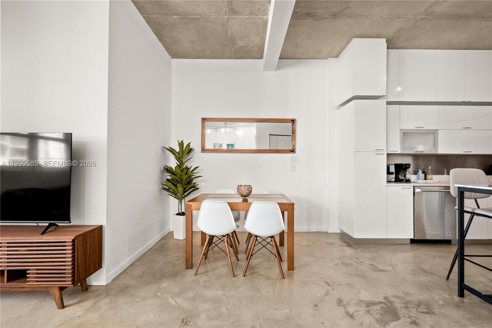 A modern dining area features a wooden table, white chairs, and polished concrete floors — 234 NE 3rd St # 1704, Miami FL 33132, MIAMI, FL