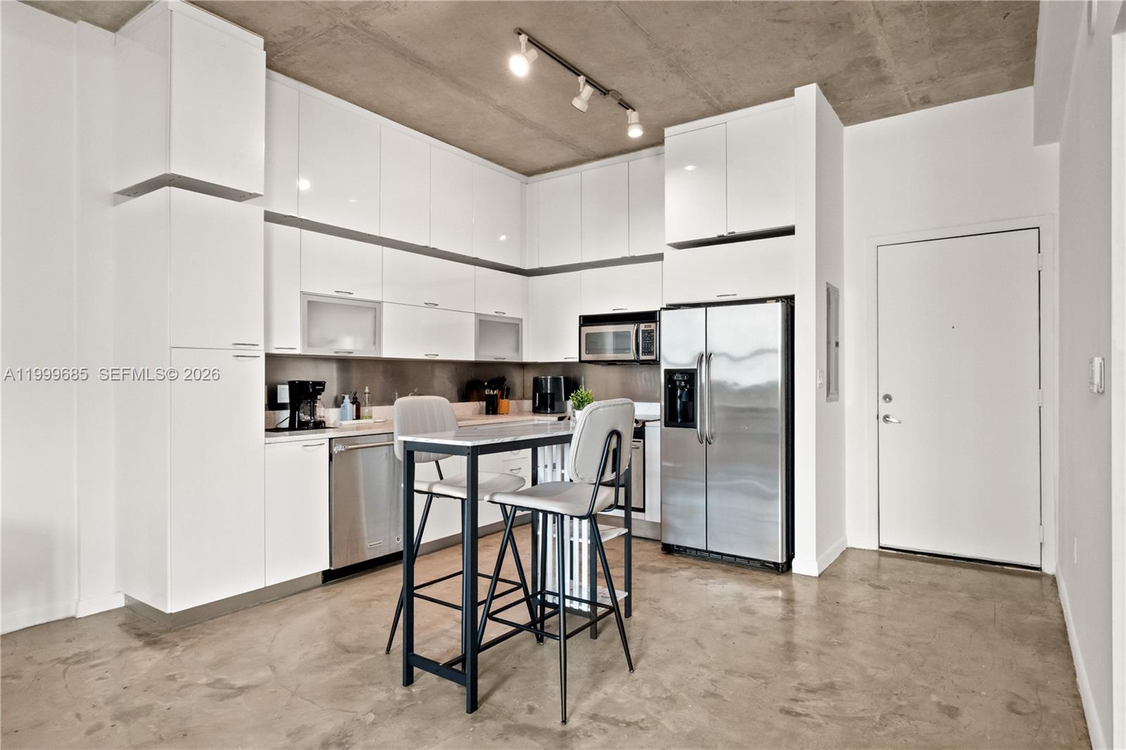 A modern kitchen features white cabinets, stainless steel appliances, and a concrete ceiling — 234 NE 3rd St # 1704, Miami FL 33132, MIAMI, FL