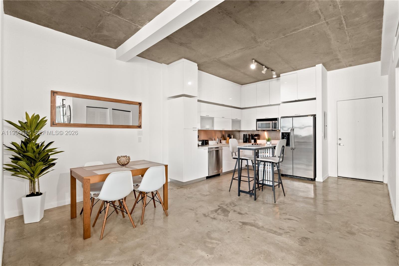 A modern kitchen and dining area feature white cabinets, stainless steel appliances, and concrete floors — 234 NE 3rd St # 1704, Miami FL 33132, MIAMI, FL