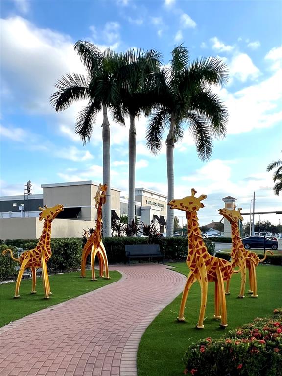 Four metal giraffe sculptures stand on a lawn beside a brick walkway and palm trees — 12468 KOENIG LANE, PORT CHARLOTTE, FL