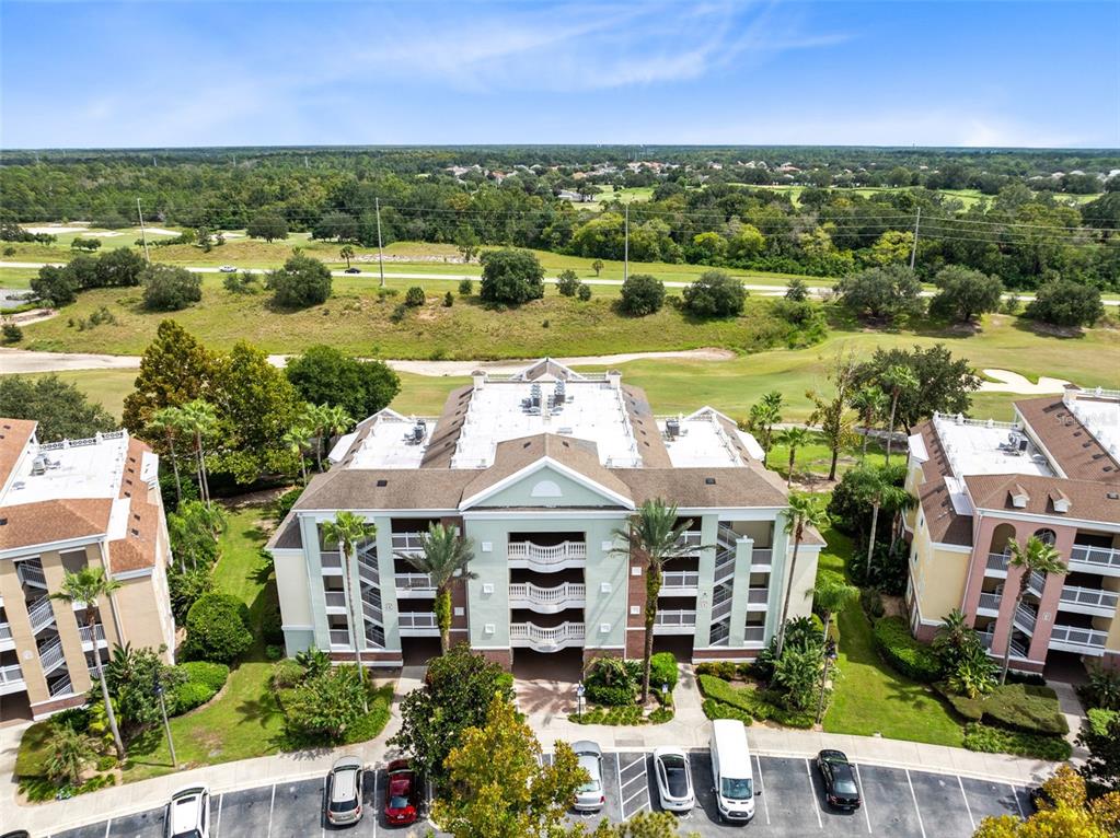 An aerial view shows a multi-story apartment building with a parking lot in front — 7602 CABANA COURT UNIT 101, KISSIMMEE, FL