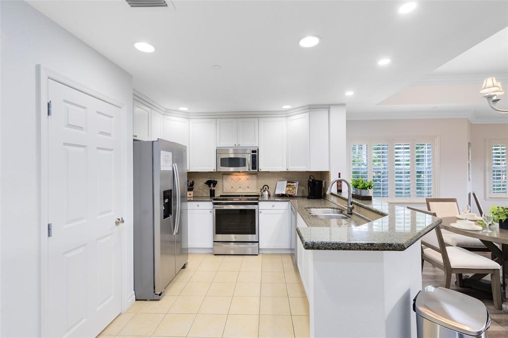 A kitchen with white cabinets, stainless steel appliances, granite countertops, and light-colored tile flooring — 7602 CABANA COURT UNIT 101, KISSIMMEE, FL