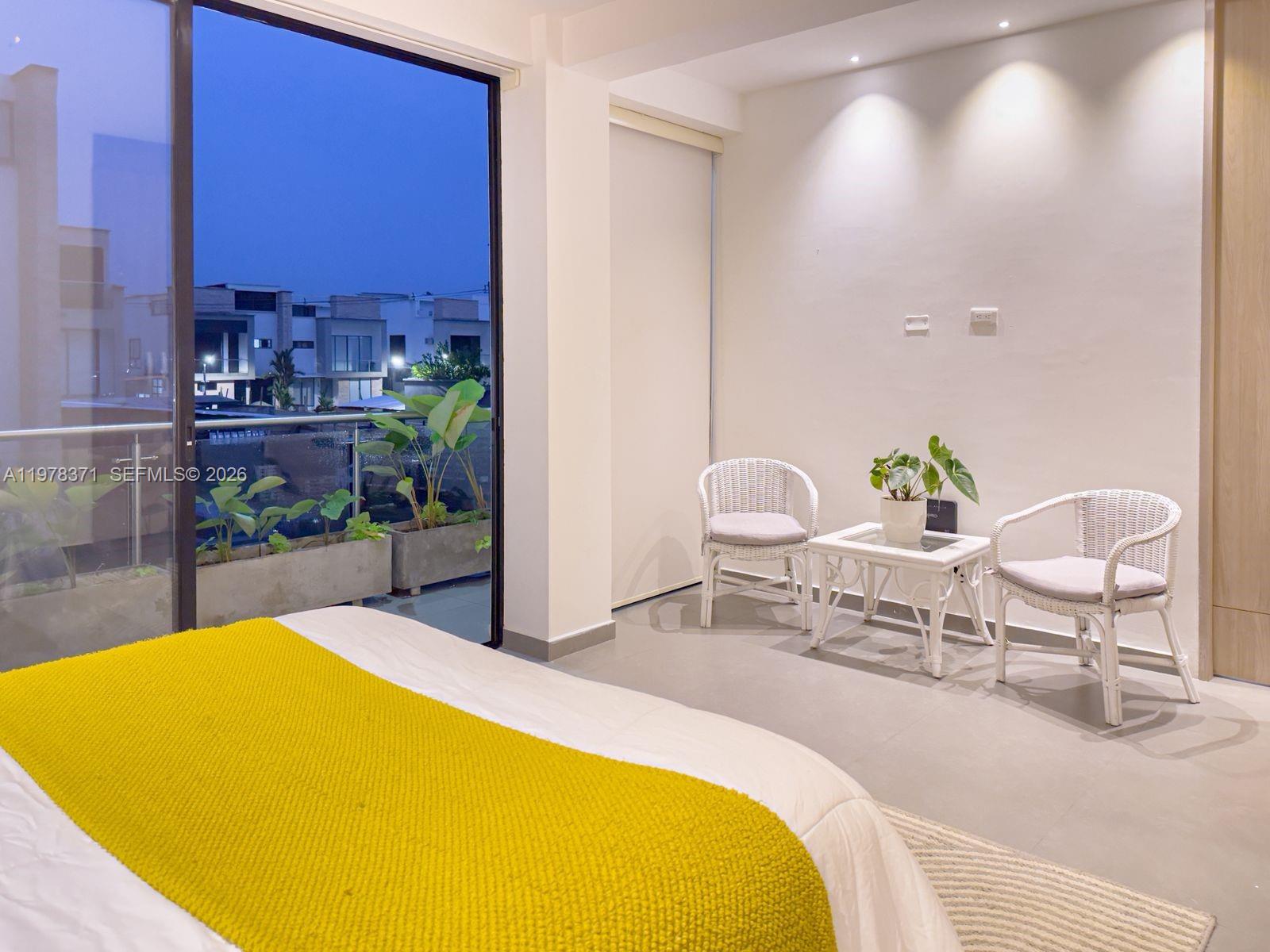 A bedroom features a yellow throw blanket, white wicker chairs, and a sliding glass door — 150 Manantial Mercededs, 764001, FL
