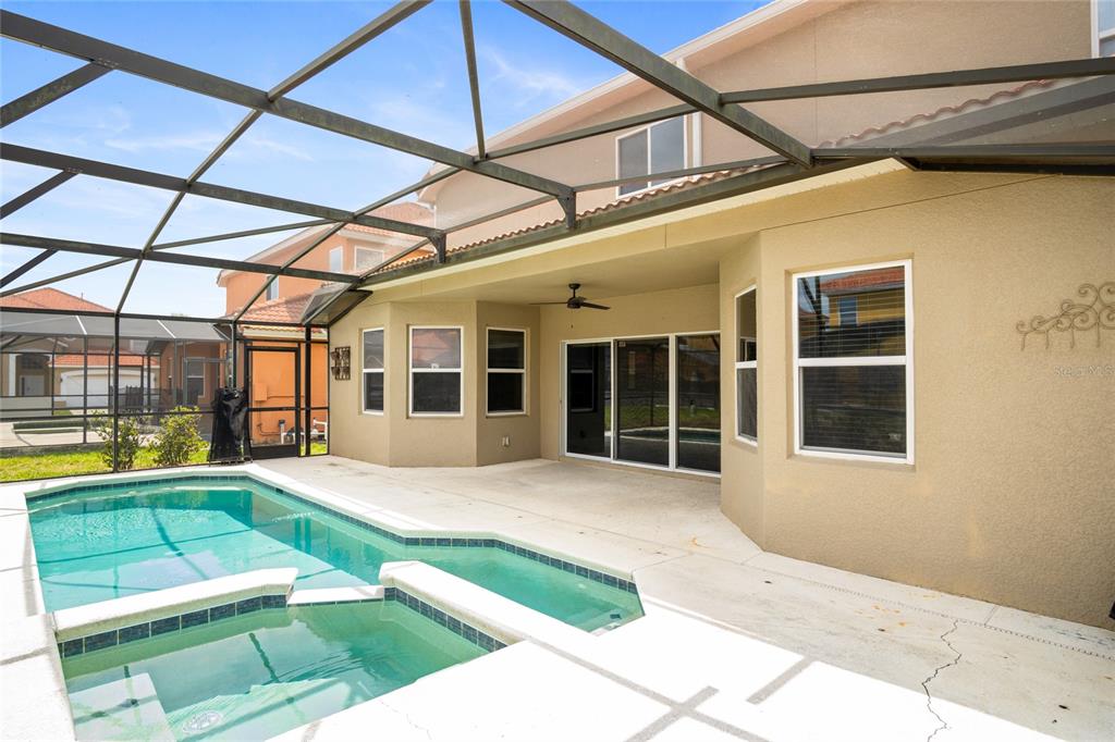 A screened-in patio features a swimming pool, a spa, and a beige stucco exterior — 118 MIRO DRIVE, DAVENPORT, FL