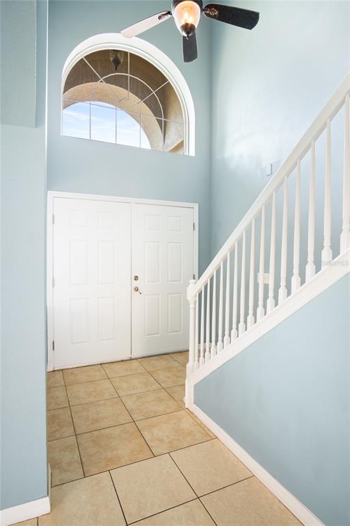 An entryway features light blue walls, tiled flooring, a white staircase, and a double door — 118 MIRO DRIVE, DAVENPORT, FL