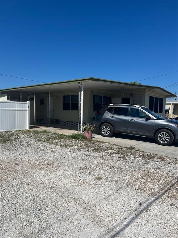 A single-story mobile home with a carport and a gray SUV parked in front — 2574 ARBELIA STREET, CLEARWATER, FL