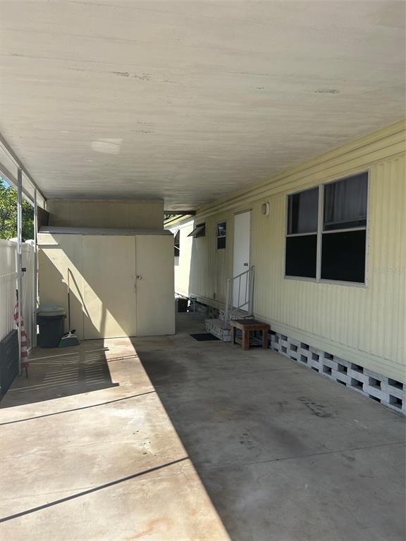 A covered carport area features a storage shed, concrete flooring, and a mobile home exterior — 2574 ARBELIA STREET, CLEARWATER, FL