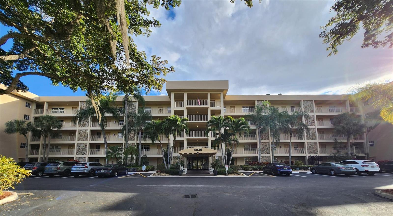 A living room features beige sofas, a glass coffee table, tile flooring, and sliding glass doors — 4030 W Palm Aire Drive # 101, Pompano Beach FL 33069, POMPANO BEACH, FL