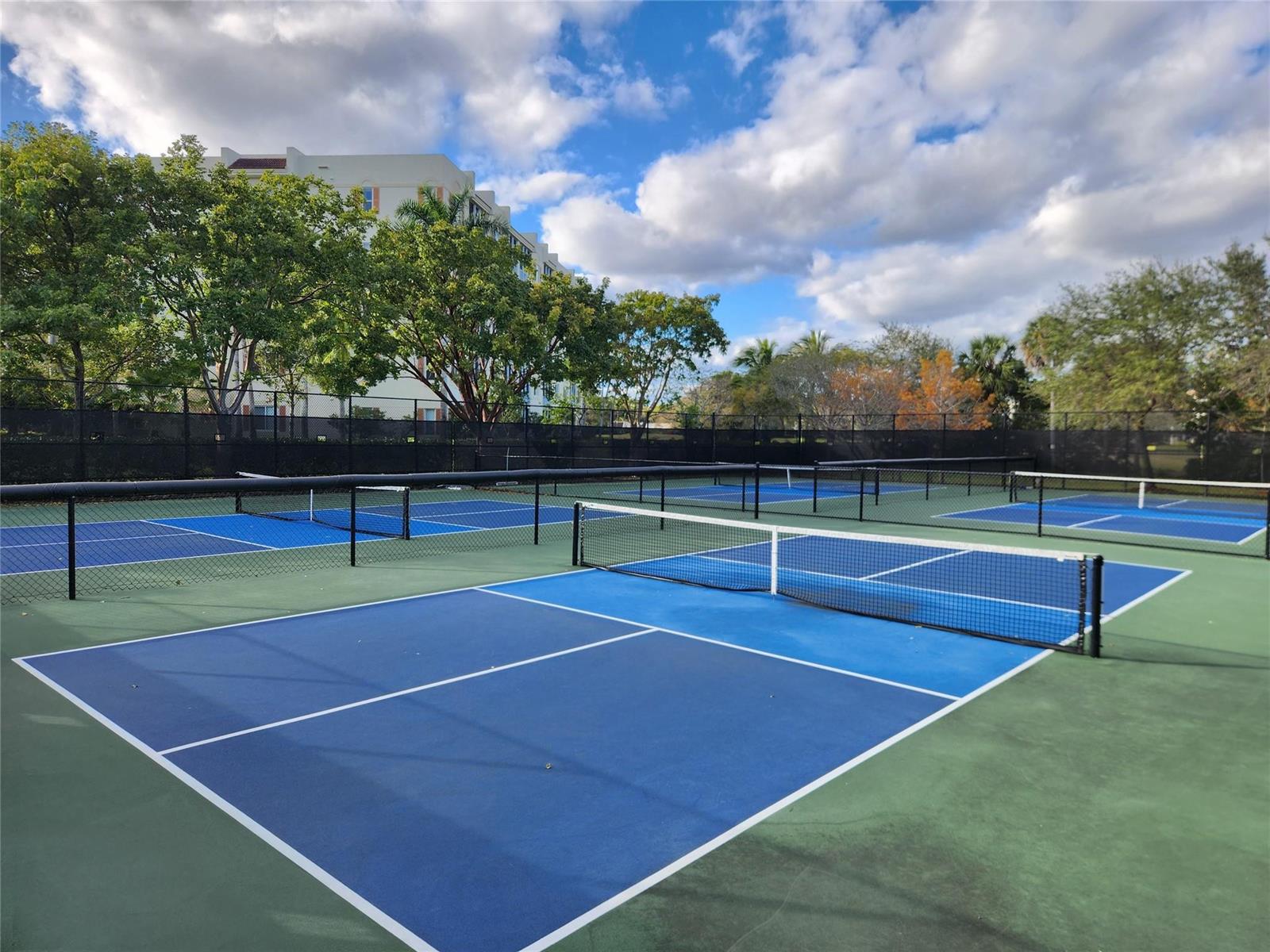 A rectangular outdoor swimming pool is surrounded by lounge chairs, palm trees, and a clubhouse — 4030 W Palm Aire Drive # 101, Pompano Beach FL 33069, POMPANO BEACH, FL