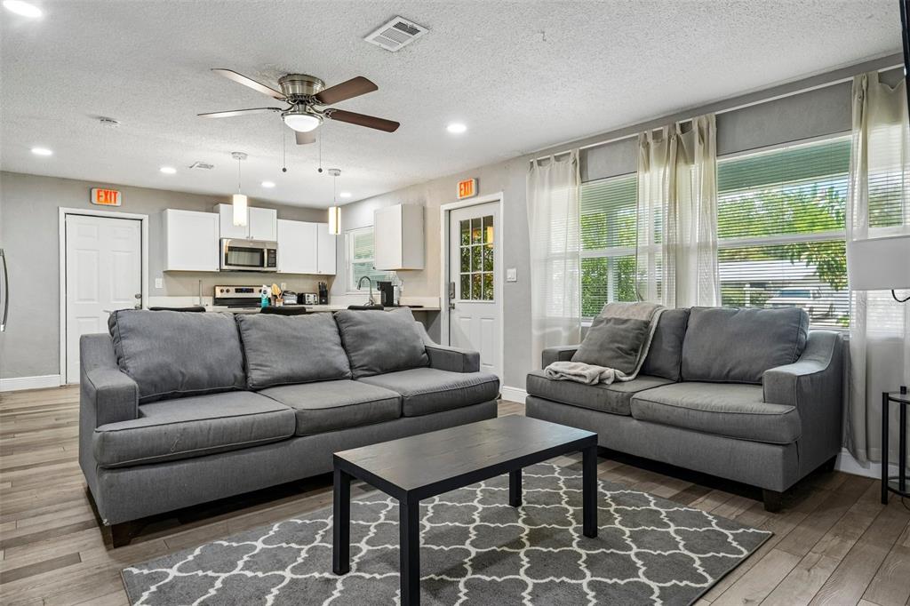 A living room features two gray sofas, a coffee table, and an open kitchen area — 520 FAIRFAX LANE, APOLLO BEACH, FL